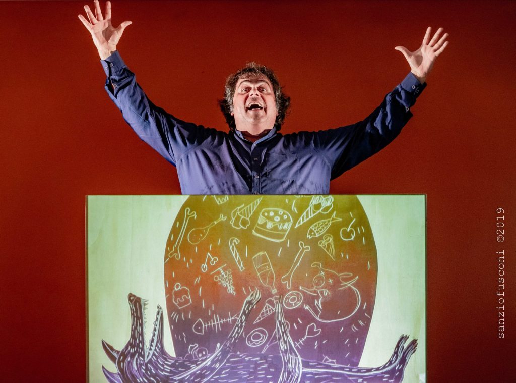 Immagine con sfondo rosso in primo piano il quadro con disegno di un lupo sdraiato e un grosso semicerchio e dietro un uomo a braccia aperte