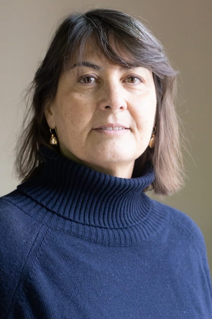 Foto dell'autrice: donna con capelli scuri e maglia a collo alto di colore blu