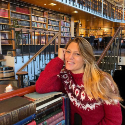 Donna sorridente con capelli lunghi biondi seduta in biblioteca